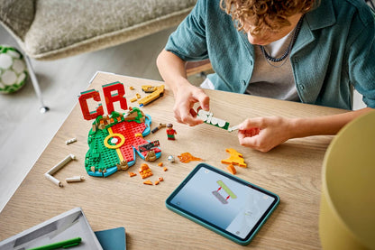 Person fitting LEGO pieces on a tabletop while assembling the CR7 soccer highlights build