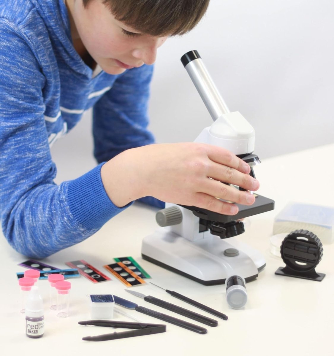 Child holding a slide while looking through a tabletop microscope