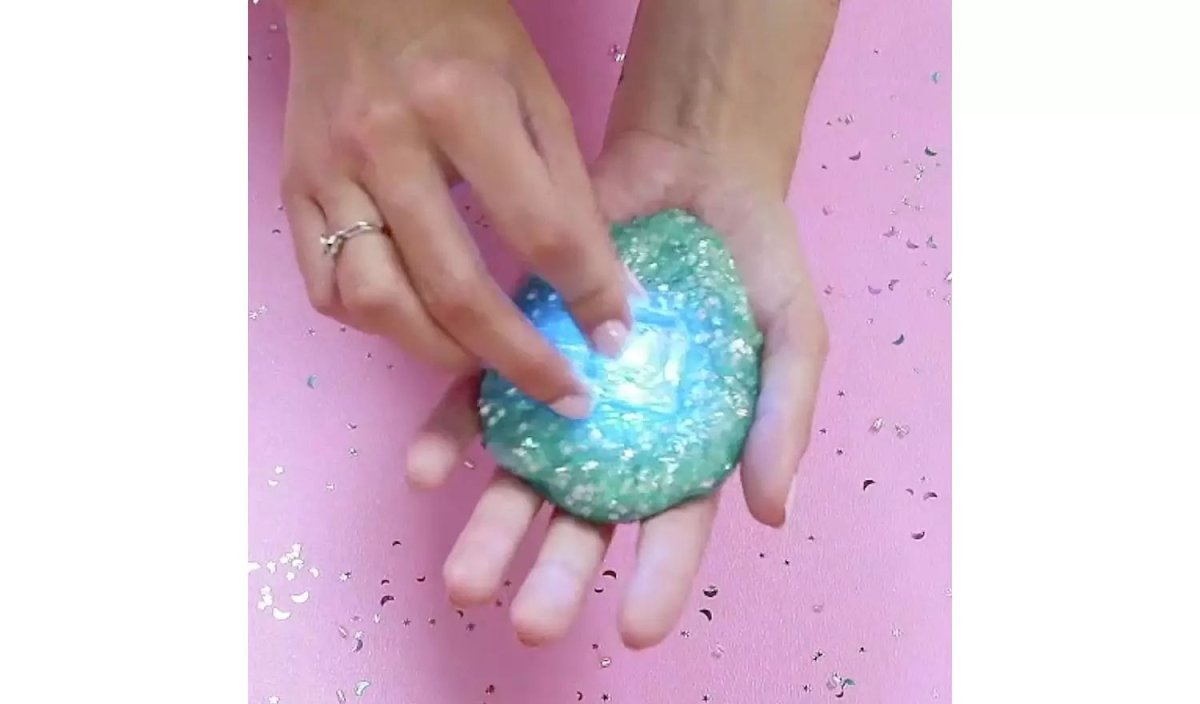 Hands holding a blue glittery light-up slime dome