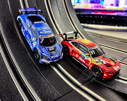 Zwei Rennwagen auf der Autorennbahn, blauer und roter DTM-Fahrwagen