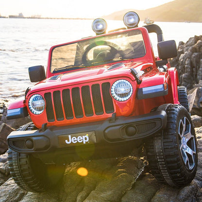 Red Jeep Wrangler Rubicon ride-on car, close-up front lights, grille, and Jeep bumper