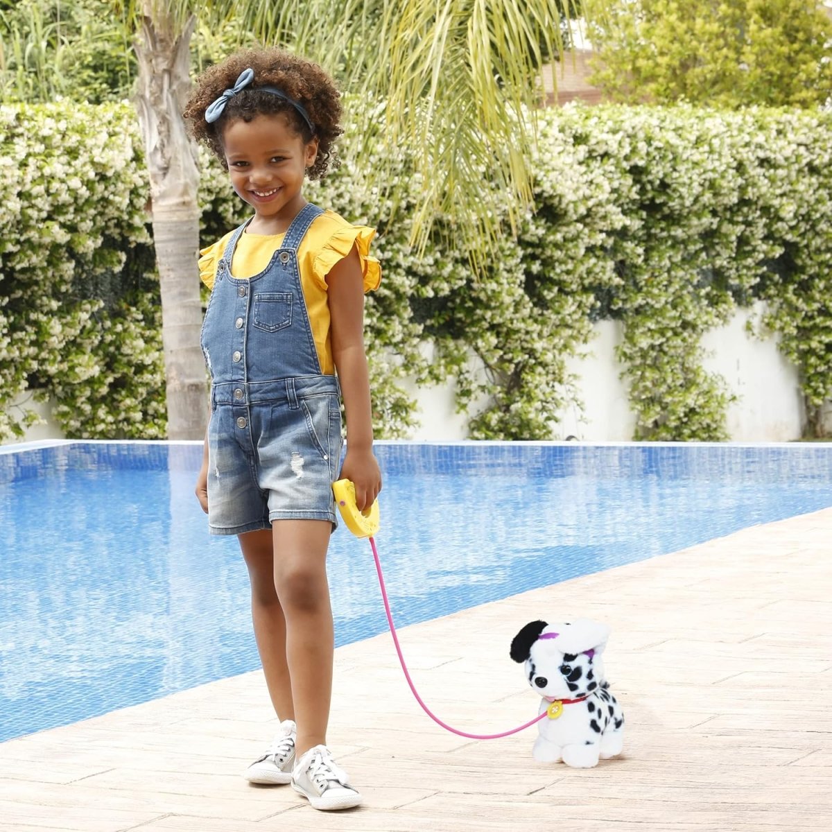 Kids using dalmatian plush puppy with pink leash beside pool