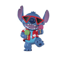 Stitch-Figur mit Sonnenbrillen, rotem Dreieck-Detail und Mini-Objekt in der Hand