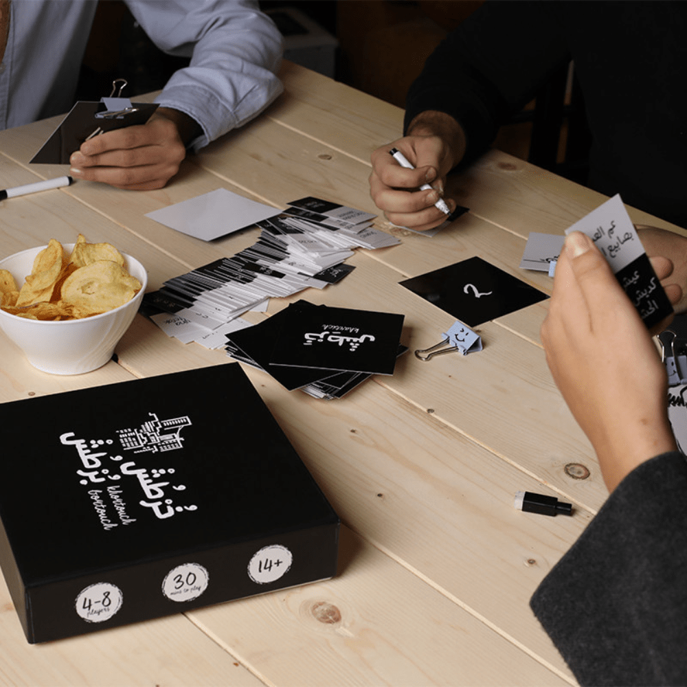 Khortouch Bortouch board game in use, players handling black game boxes and cards