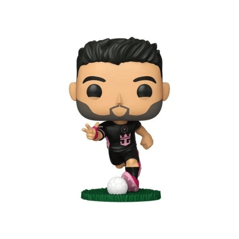 Figura de Luis Suárez con camiseta negra, pantalón y botas rosadas, sobre césped verde.
