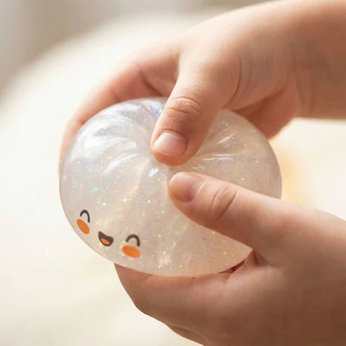 Hand-pressed glitter dumpling squishy with iridescent sparkle and smiling face
