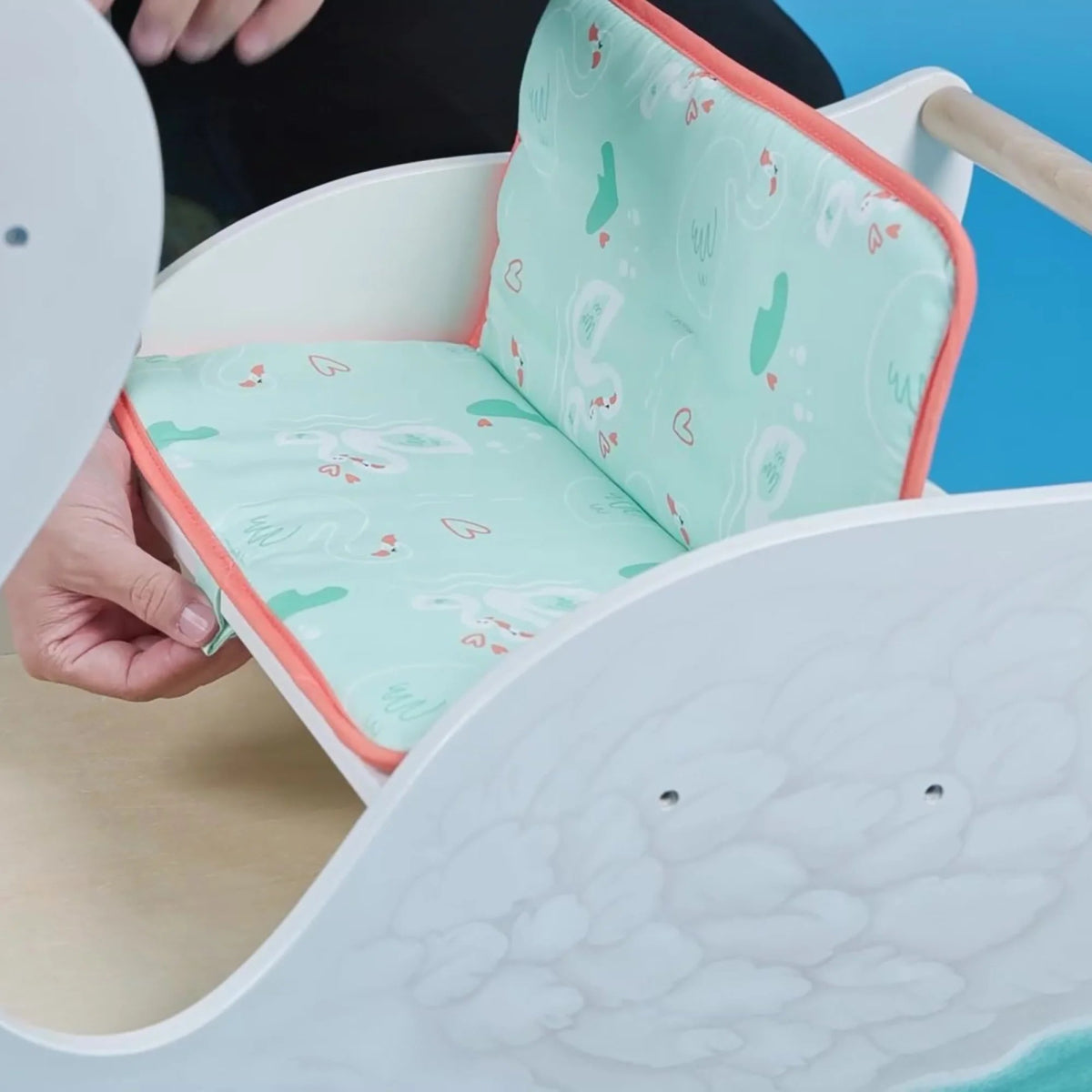 Close-up of swan cradle seat with aqua fabric and orange piping trim