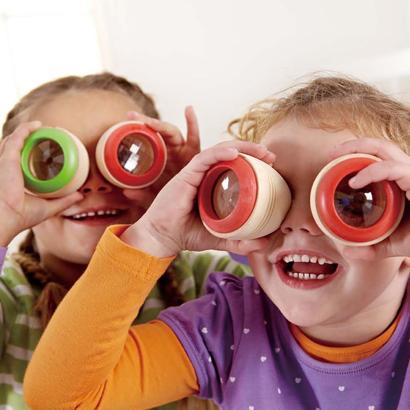 Wooden kaleidoscopes held by children, with green and red ring lenses
