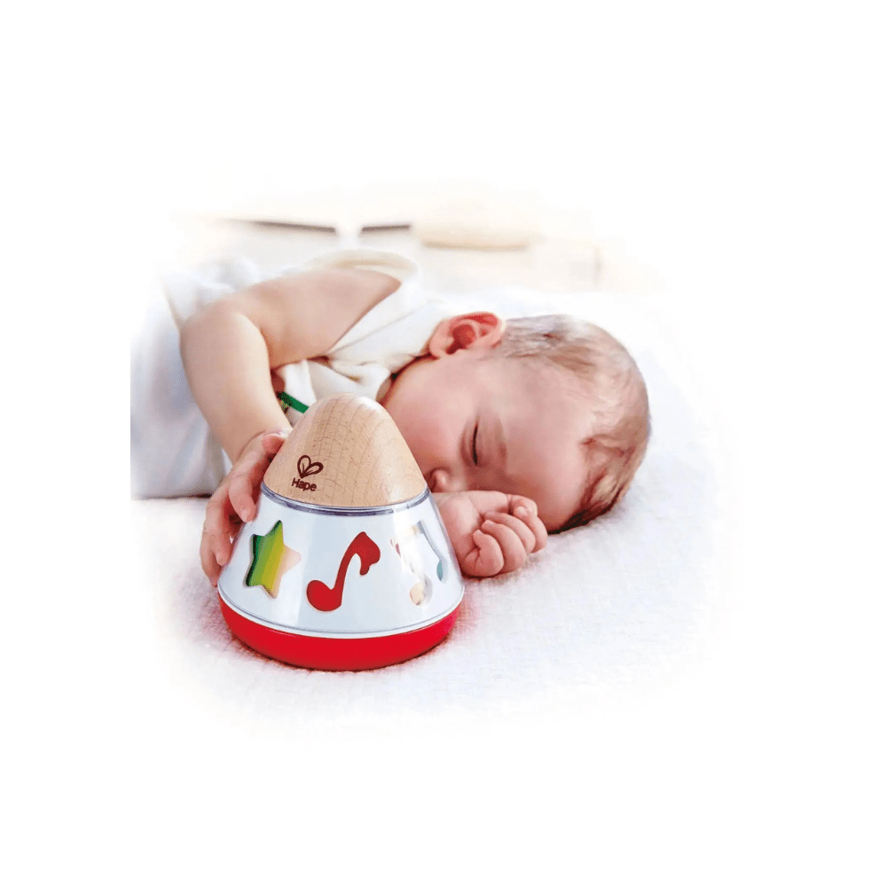 Rotating music box toy on floor, held by hands; wooden top with musical note cutouts