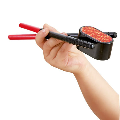 Hand holding black chopsticks with red ends over play sushi piece