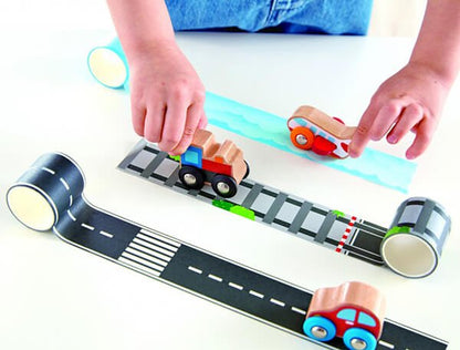 Tape and roll train toy with wooden cars on black-and-gray tape track playmat