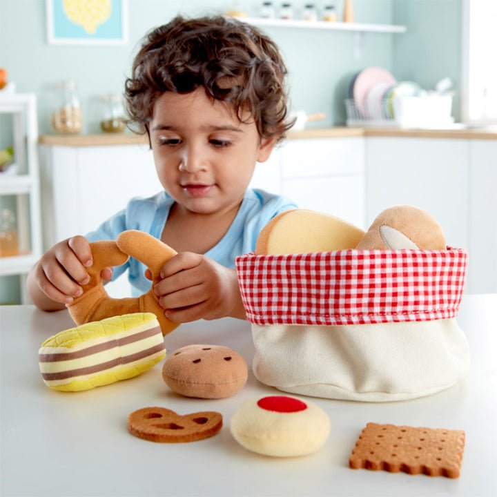 Child playing with a toy bread basket filled with assorted pretend bread pieces