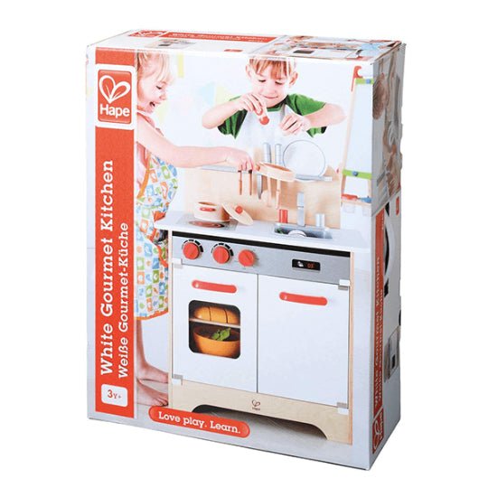 White gourmet play kitchen toy with red knobs and oven door in retail box