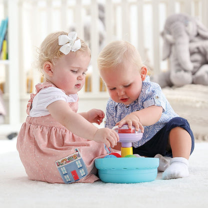Baby playing with turquoise spinning top set, purple top and yellow stem on floor