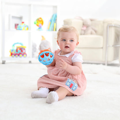 Baby holding a blue roll ball toy with clear window panels on its face