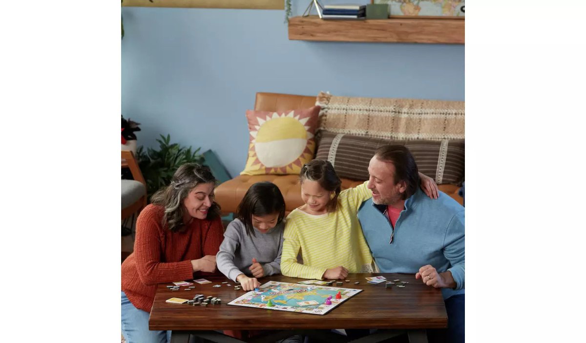 Family playing Monopoly Travel World Tour board game at a table with a map board