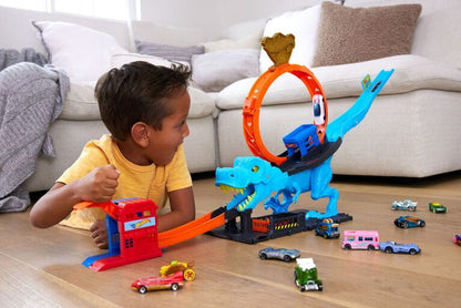 Blue T-Rex chomp down playset with orange ring, gray base, and colorful cars on floor
