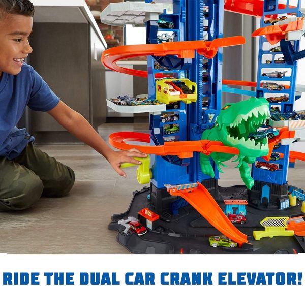 Toy car track garage set with orange elevator, blue tower, and green T-Rex dinosaur