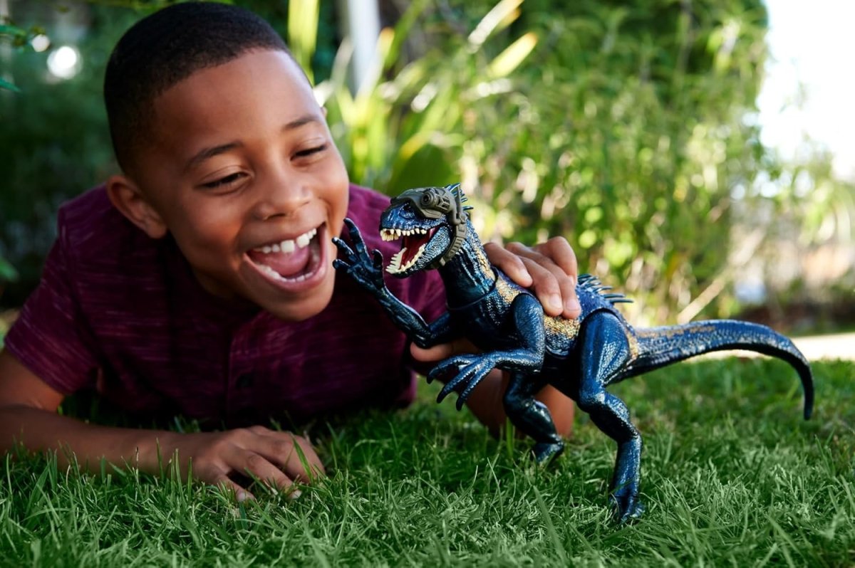 Indoraptor dinosaur toy figure held by a child outdoors, dark blue-black with claws