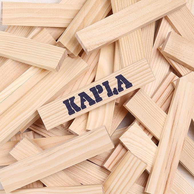 Pile of light-wood building blocks with printed Kapla logo on one plank