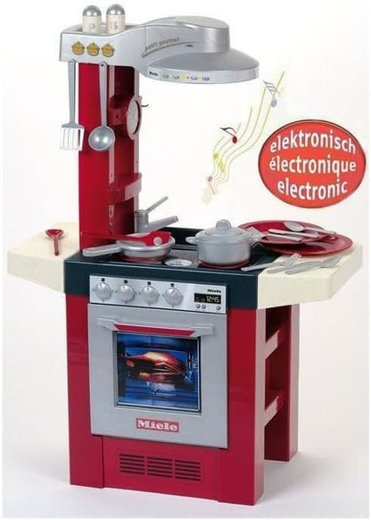 Miele toy kitchen set with red cabinet, silver range hood, oven door, and cookware