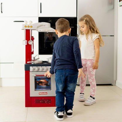 Red Miele toy kitchen set with oven window, stovetop, and cookware, side view