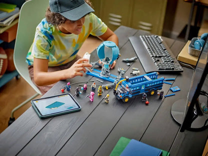 Child assembling the Battle Bus model from blue-and-gray LEGO pieces at a table