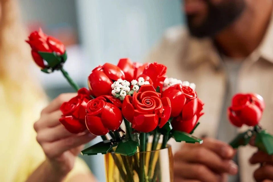 Handheld bouquet of red roses with white buds, green stems