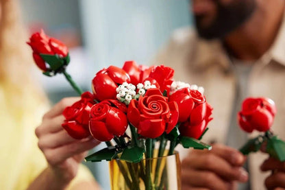 Handheld bouquet of red roses with white buds, green stems