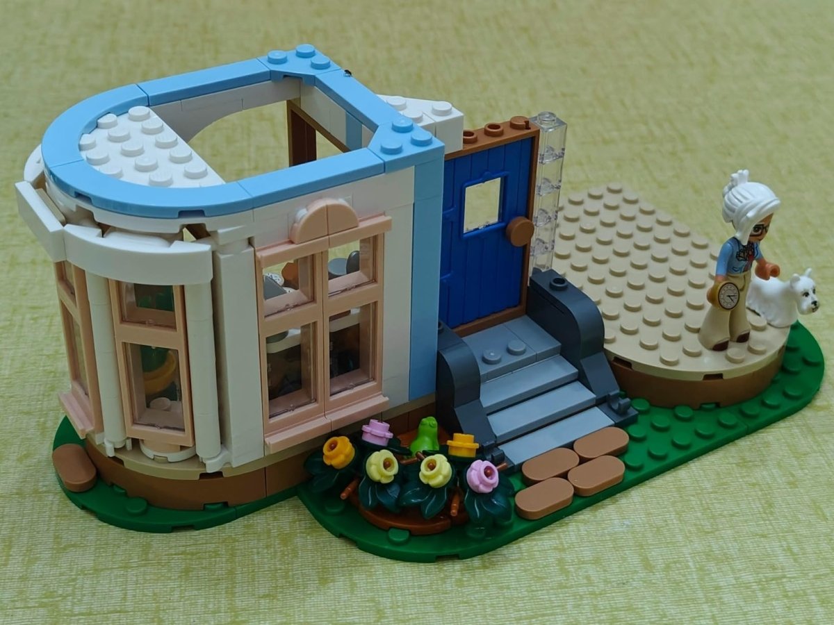LEGO castle side build with blue door, brown railings, and a small outdoor garden