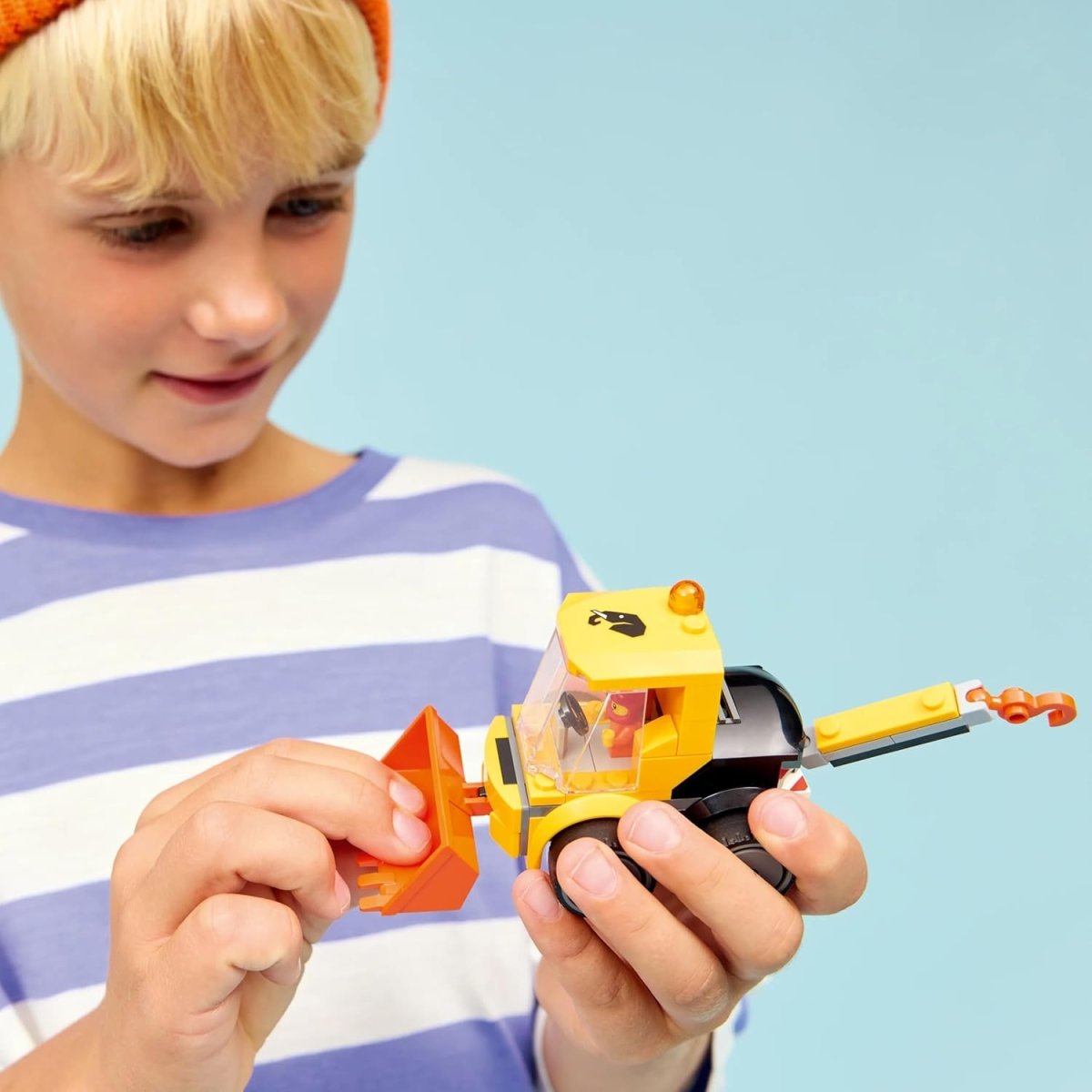 Child holding yellow wheel loader with orange bucket and clear windshield