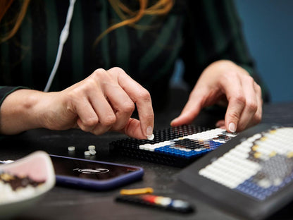 Person placing LEGO beads on a Mickey Mouse mosaic base