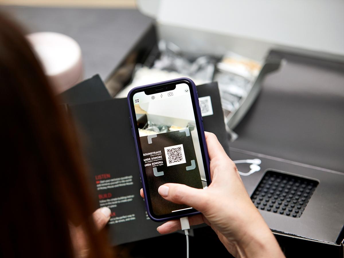 Hand holding phone to scan a QR code on the Mickey Mouse LEGO manual