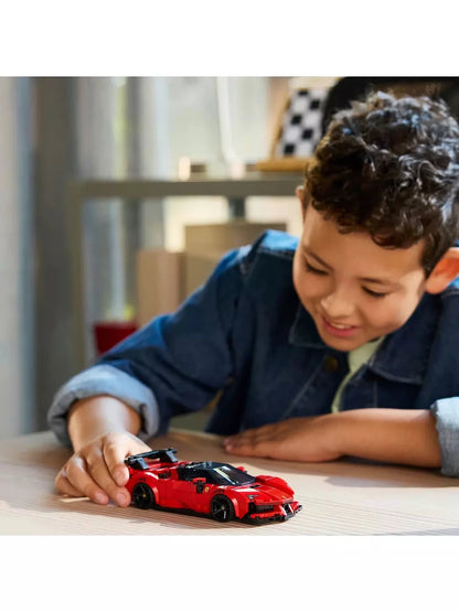 Red SF90 XX Stradale model car on table, child hand placing it
