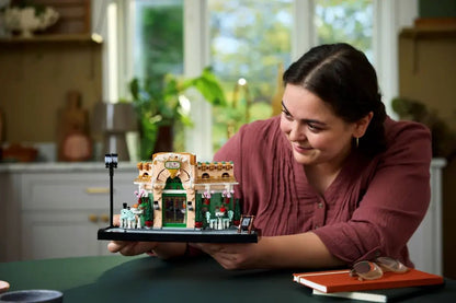 French Café LEGO, set sur socle noir tenu dans les mains : porte verte et façade beige