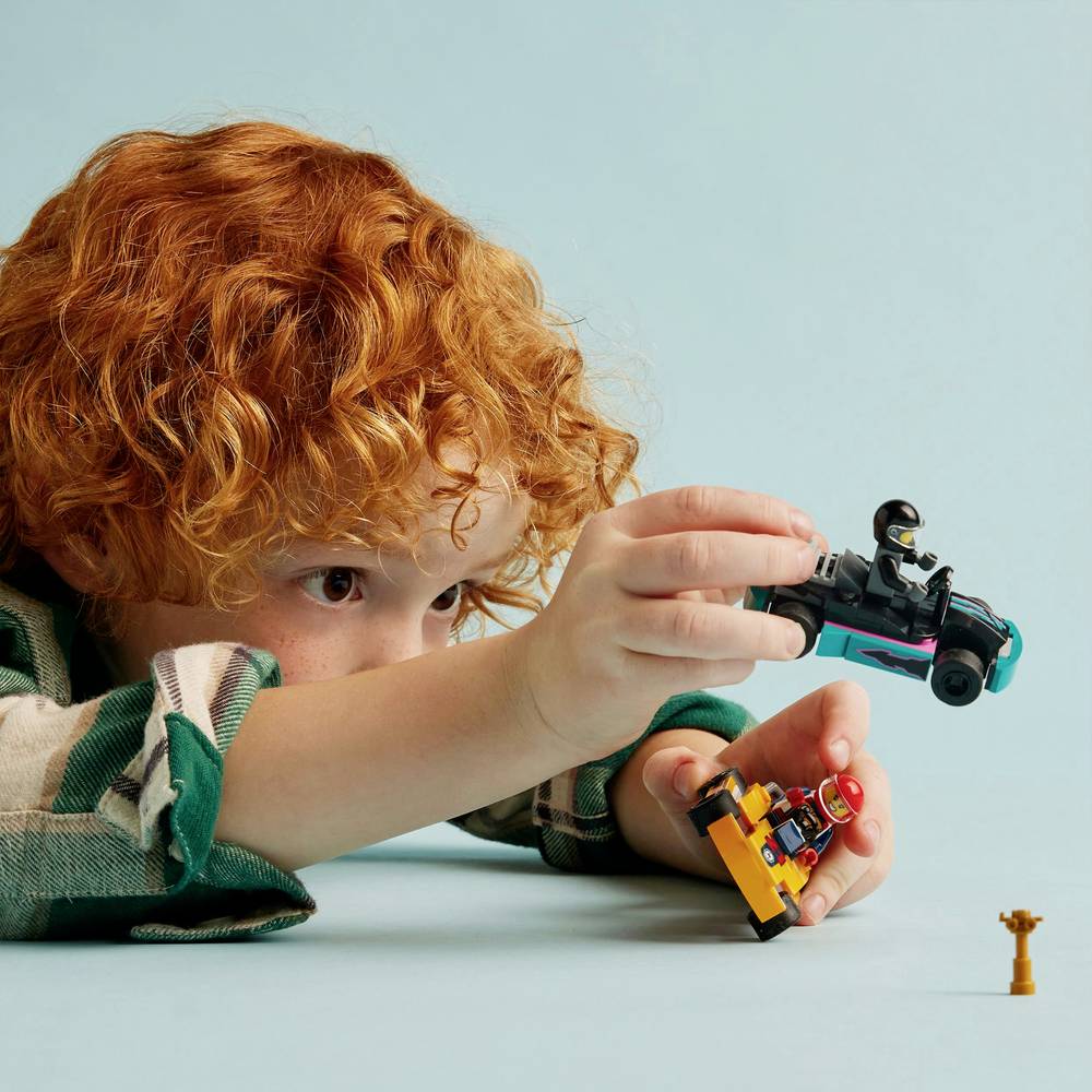 Go-kart toy set with child holding a yellow and teal race car and minifigure driver