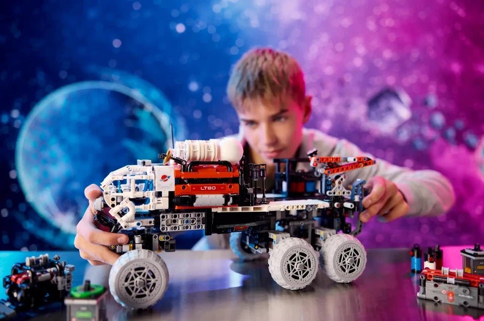 Person holding the Mars Crew Exploration Rover Technic model with gray wheels and arm