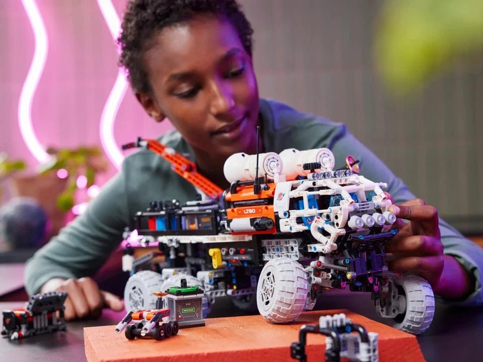 Child holding the Mars Crew Exploration Rover Technic model with orange engine details