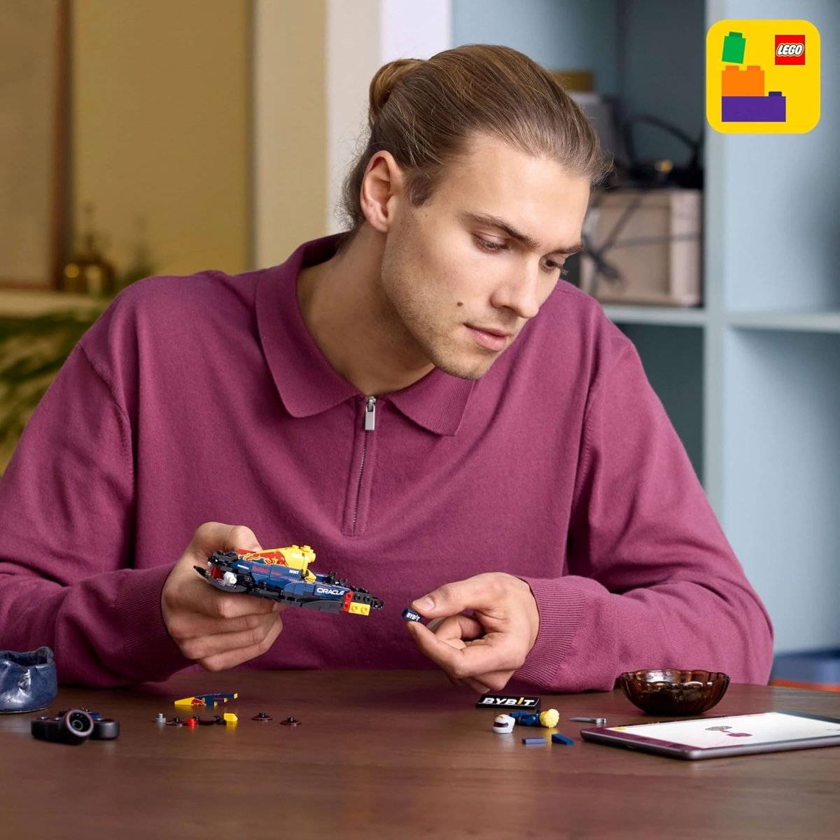 Person assembling LEGO RB20 F1 race car model, holding the small vehicle pieces