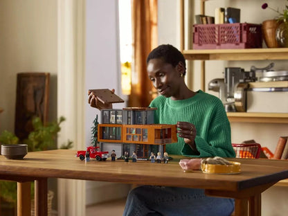 Girl holding The Cullen House LEGO set; orange two-story house model with minifigures and truck