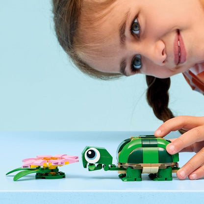 Hands play with green LEGO turtle and pink water-lily flower set