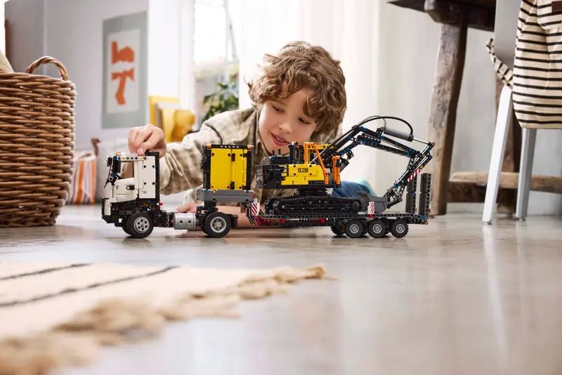Kind spielt mit Volvo FMX Bagger-LKW LEGO Modell, gelber Aufbau und Kettenantrieb