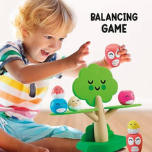 Wooden tree balancing game with child and colorful smiling bird pieces