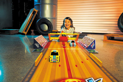 Toy car race track playset with small cars on orange lanes and ramps
