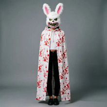 Rabbit mask with snarling grin; white hooded cloak with red splatter over black outfit