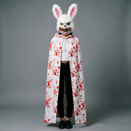 Rabbit mask with snarling grin; white hooded cloak with red splatter over black outfit