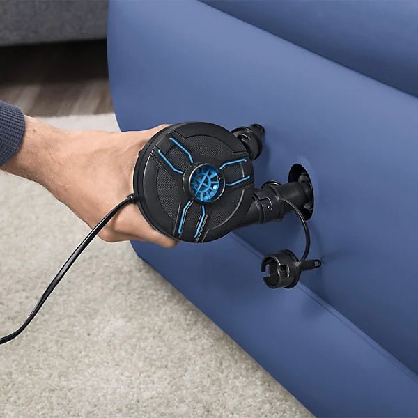 Hand using AC/DC air pump nozzle on inflatable mattress, black pump with blue details