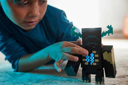 Warden collectible figure held by a person, black-and-blue pixel armor