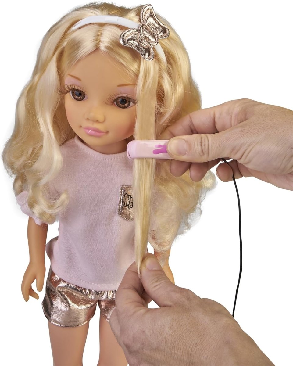 Blonde beauty doll with pink shirt and silver shorts while a hand styles her hair