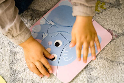 Child assembling a blue animal jigsaw puzzle piece on a mat